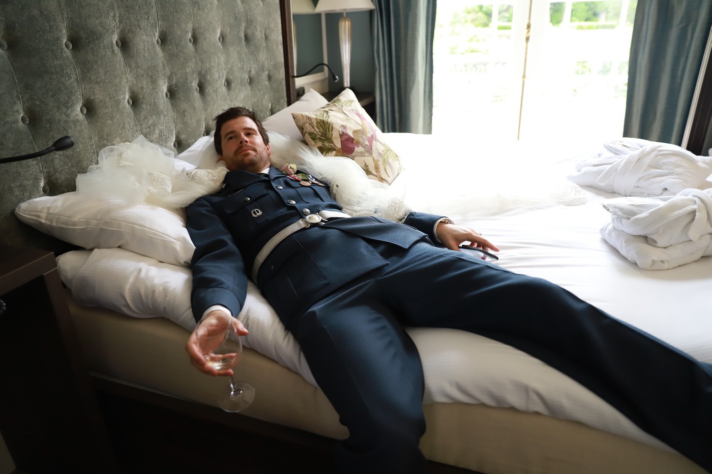 Bräutigam ruht in Uniform auf dem Hotelbett