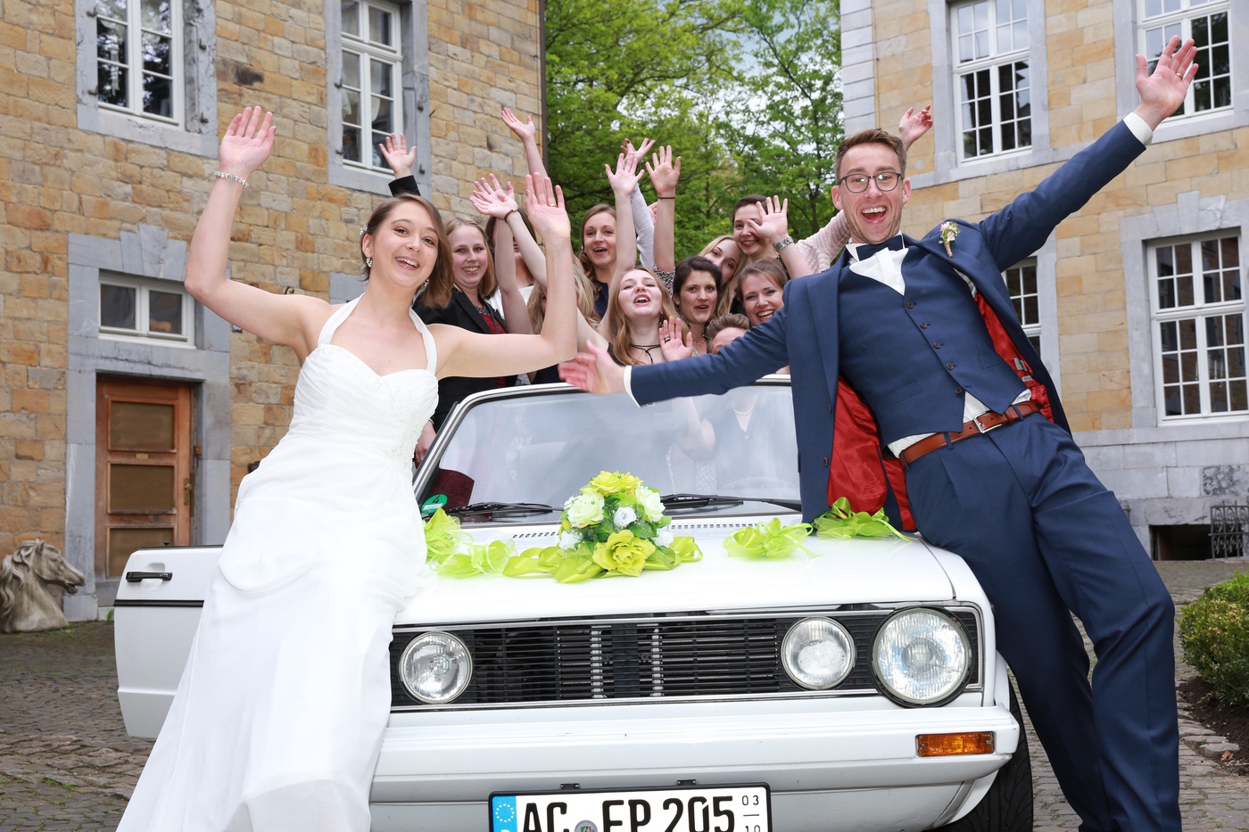 Brautpaar und Freunde jubeln auf dem Oldtimer